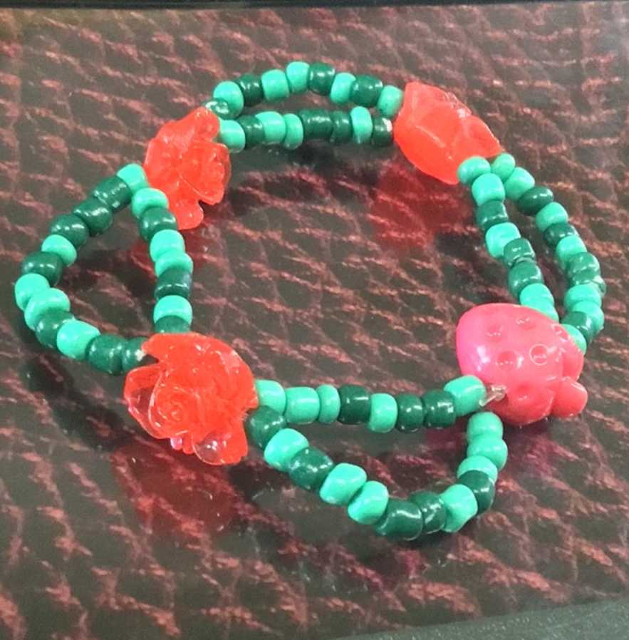 Single with alternating green, dark green, rose, and strawberry beads! Which is further decorated with lace-like bead stem.